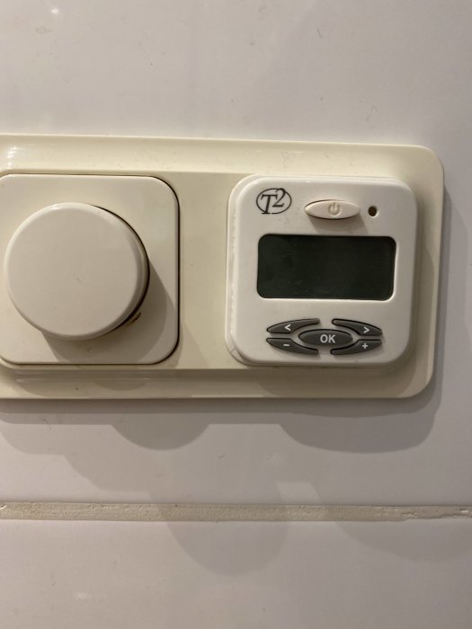 Termostat med vridknapp och digital display för inställning av rumstemperatur.