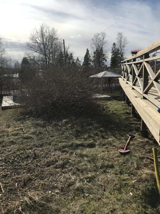 Existerande träaltan angränsande till en öppen gräshöjd där en utbyggnad och installation av spabad planeras.