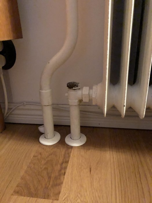 Anslutningsrören till en gjutjärnsradiator i en bostad med fråga om dimensionering för utbyggnad.