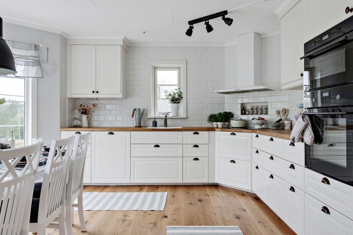 Ett nyrenoverat kök med vita skåp, träbänkskiva och infälld belysning.