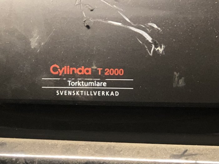 Etikett på Cylinda T 2000 torktumlare, med texten "Svensktillverkad". Repor och smuts syns på ytan.