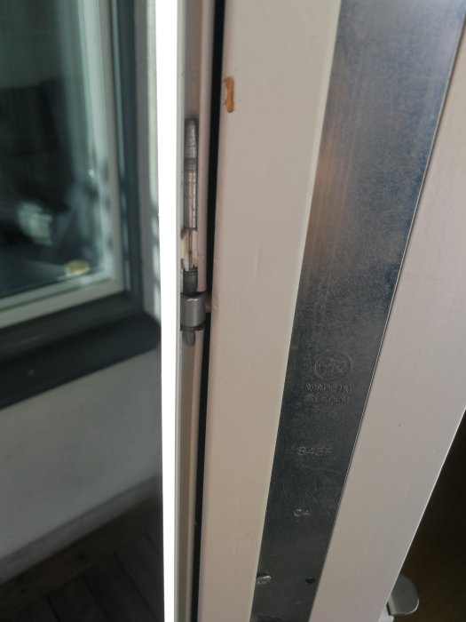 Närbild på en dörr med synlig dörrgångjärnsmekanism mellan öppen dörr och karm.