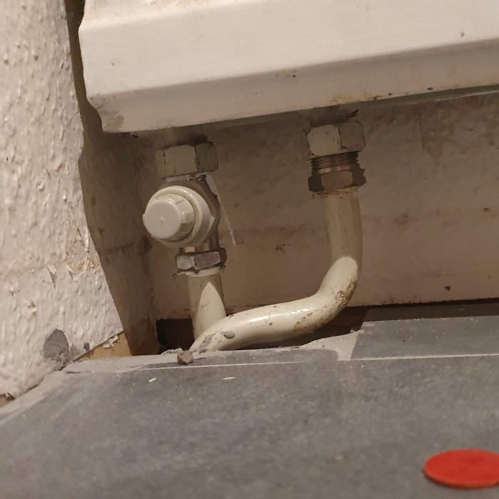 Avstängd radiator med lock på ett röranslutning under köksskåpet, indikerar ett 1-rörssystem.