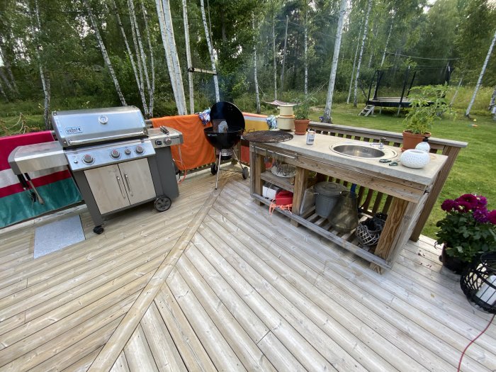 Trädäck med grill och utomhuskök, väl underhållet efter fem år, med natur i bakgrunden.