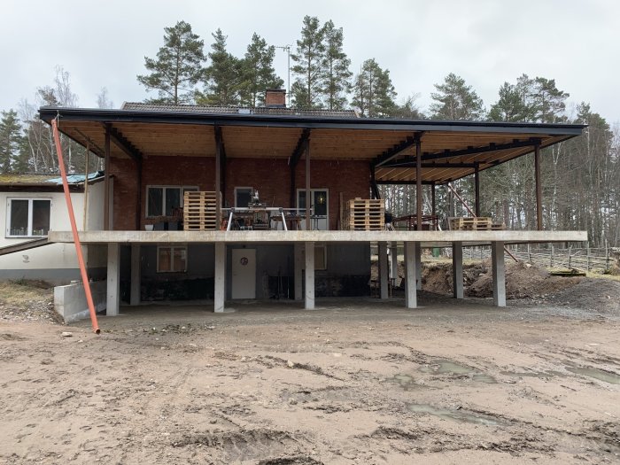 Ett hus under renovering med blottade grundpelare och tillbyggd veranda under konstruktion.