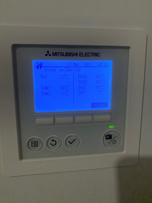 Display av Mitsubishi Electric luftvattenvärmepump som visar temperaturavläsningar, med olika värden på skärmen.