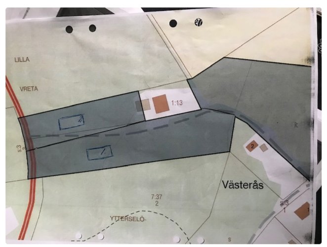 Karta som visar en fastighet, intilliggande byggnader och en asfaltväg, potentiell tomtmark och servitut.