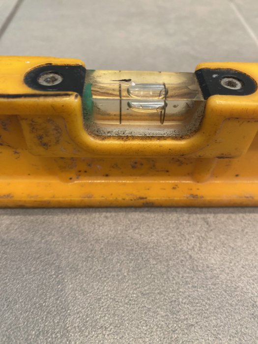 Gul vattenpass avbildat nära, bubblan indikerar möjlig ojämn yta.