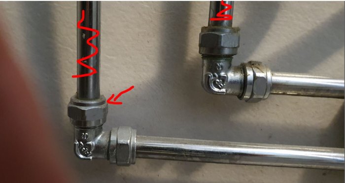 Vinkelkoppling och rör markerade med röd text på vägg, sökande efter rätt lock för 1/2 tums rör.