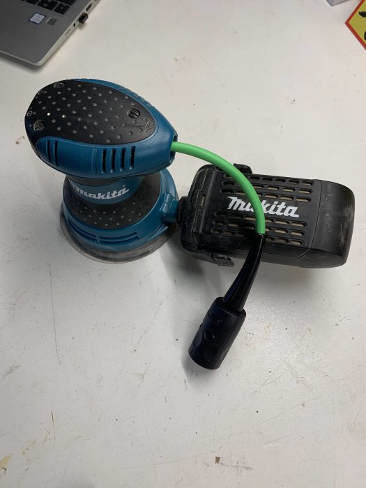 En Makita slipmaskin på ett bord med en nyligen installerad grön Festool plug it-kabel.