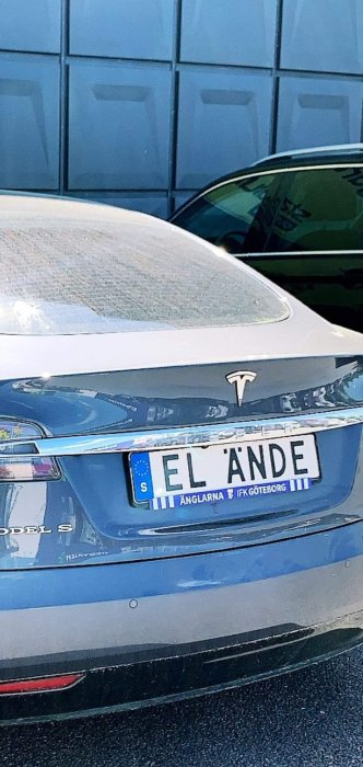 Bakdel av en Tesla Model S med personlig skylt "EL ÄNDE" framför blå väggyta.