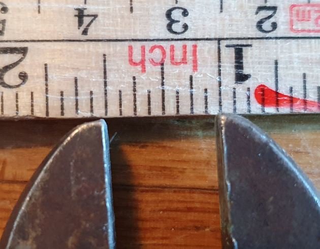 En skiftnyckel som håller ett måttband mot träbakgrund, används som improviserat mätverktyg.