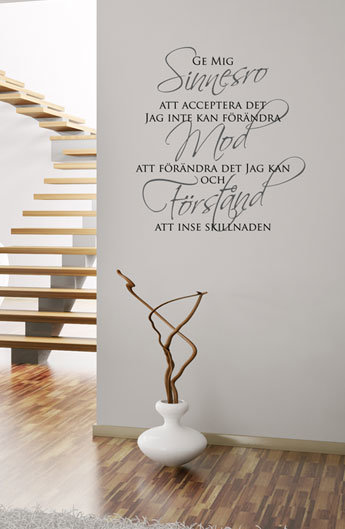 En vit vägg med inspirerande text och en vit vas med grenar framför trätrappor.