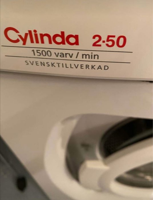 Etikett på en Cylinda 2-50 tvättmaskin som visar 1500 varv/min och texten "Svenstillverkad", del av trumman synlig.