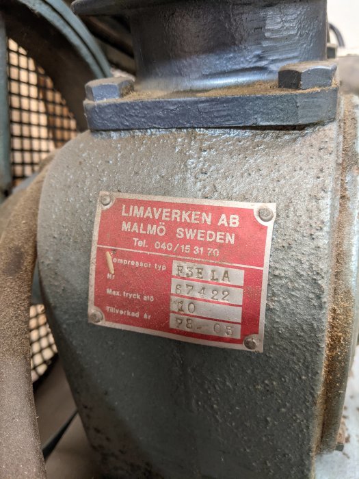 Äldre kompressor från Limaverken AB med typskylt och tillverkningsår 1976 synlig, dammig och verkar robust.