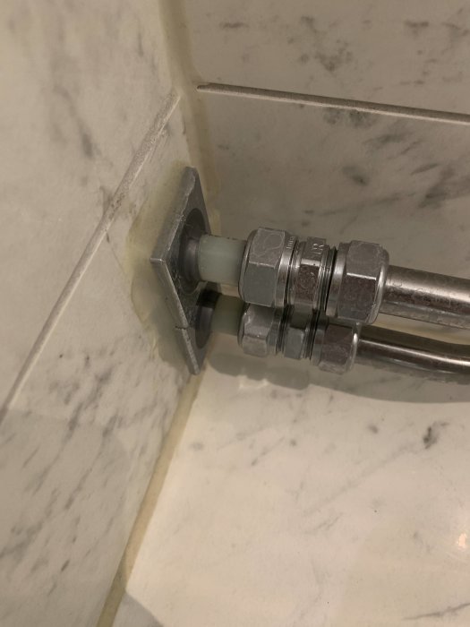 Närbild på röranslutning bakom toalett med dålig tätning och synliga smutsavlagringar.