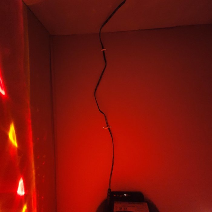 Elektrisk installation med skarvad kabel fixerad med eltejp och en strömbrytare vid en röd vägg.