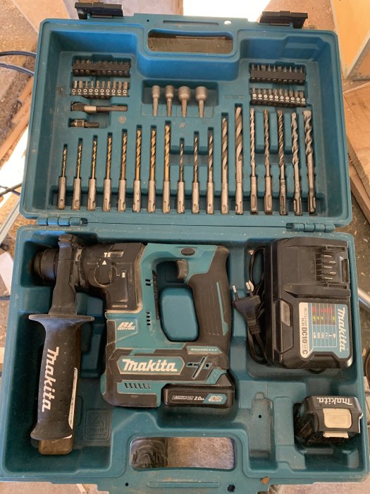 Makita verktygsuppsättning i öppen väska inklusive borr, skruvbits, hammarborr, batterier och laddare.
