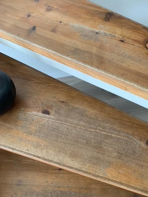 Sliten trätrappa med synliga användningsspår och vita sidor i behov av renovering.