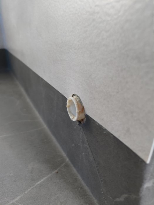 Närbild på oskarp badrumsmatta vid rörutstick med synliga skarvar och rester av tejp.