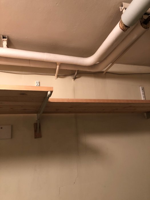 Vattenledning med missfärgning längs röret och spår på väggen nedanför i ett pannrum.