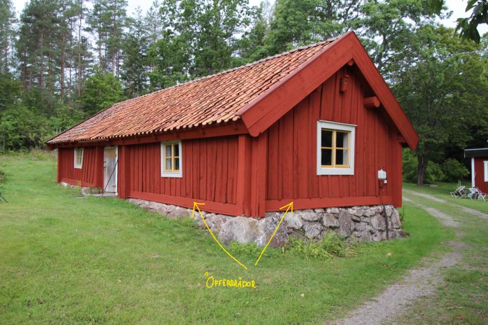 Rödmålad stuga med offerbrädor utpekade, tegeltak och traditionell träpanel.