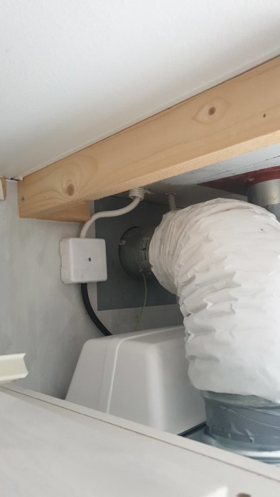 Värmepumpinstallation med synlig isolerad ventilationskanal och elanslutning.