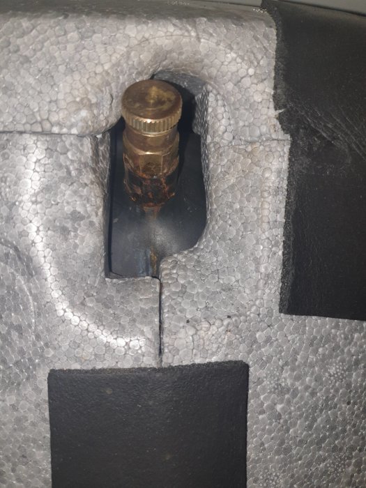 Rostig infästning av luftningsventil på IVT greenline ht plus med vit isolering som bakgrund.