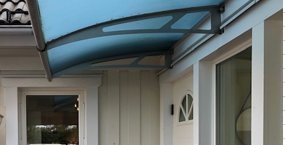 Blågrön ersättningsplastinstallerad som tak över en veranda på ett vitt hus.