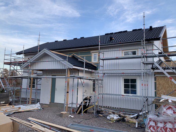 Ett hus under renovering med ställningar, salningar och foder som installeras på utsidan.