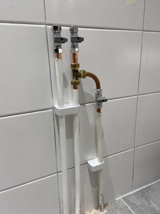 Väggmonterade prisolrör och kopplingsventiler för kommodinstallation.