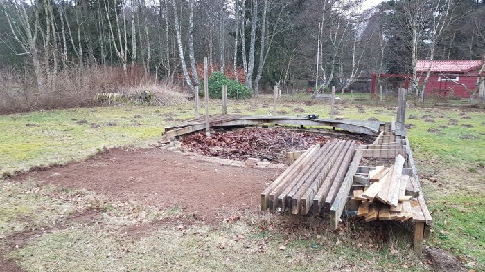 Före detta plats för pooldäck med bjälklag och staplar av bärreglar i en trädgård.