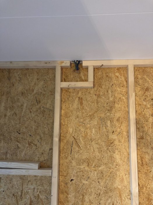 Elektriska kablar sticker ut från ett öppet utrymme i en regelvägg med OSB-skivor, redo för vidare installation.