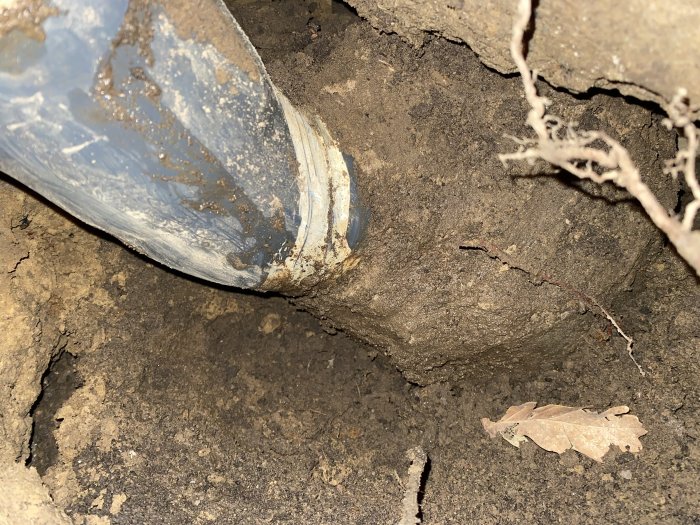 Sprucket anslutningsrör mellan stuprör och dagvattenledning under markbildande slukhål.