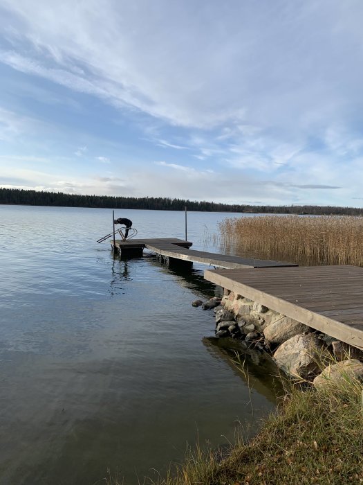 Brygga med extra tunna nära vattenkanten, bilar upp bryggan med bil, klart himmel.