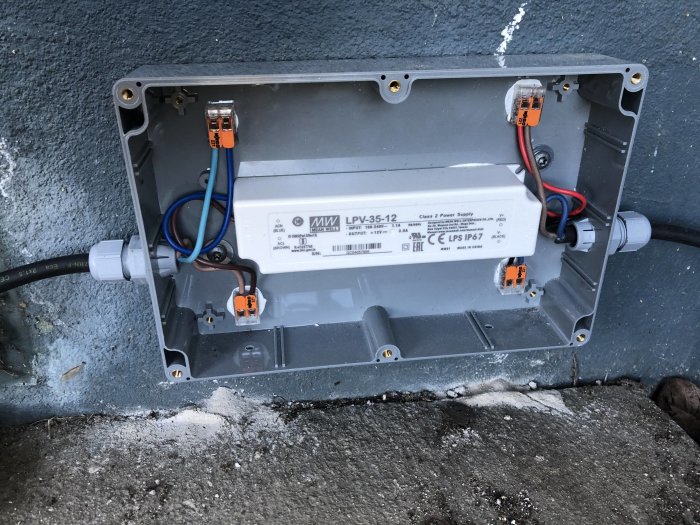 Infälld LED-slingans elanslutning i plastlåda på betongvägg med tjockare sladd och kabelgenomföringar.