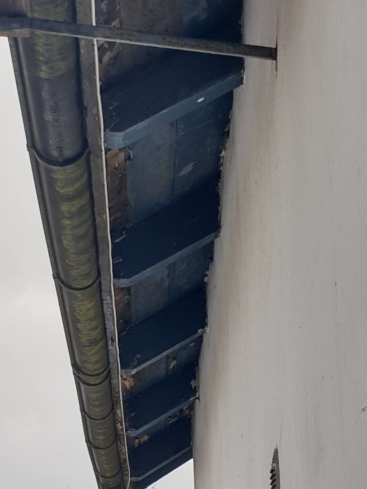 Nedgången takfot i behov av renovering intill ett stuprör på ett hus.