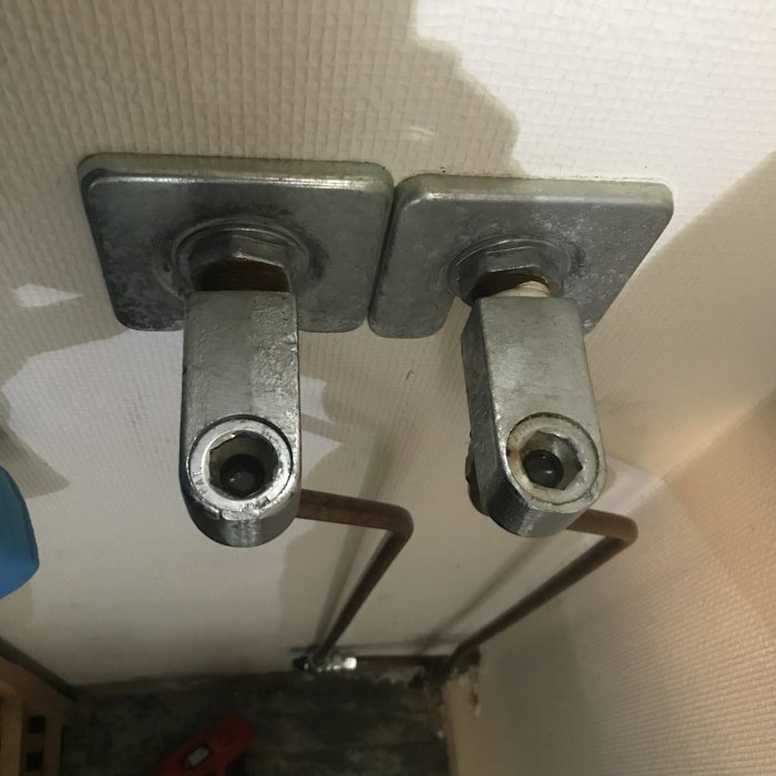 Två metallkranar för vattenslang ovanför en bakgrund av vit isolering och betongvägg.