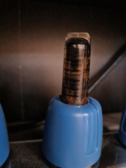 Närbild på en flödesindikator med missfärgningar, vilken är monterad på en blå fördelarenhet.