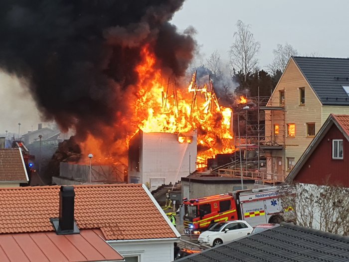 Nybyggt hus i cellplast som brinner kraftigt med rökutveckling, brandkår på plats.