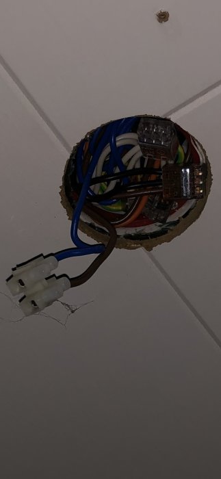 Ett öppet eluttag i taket med synliga kablar och kopplingsklämmor, redo för installation av takplafond.