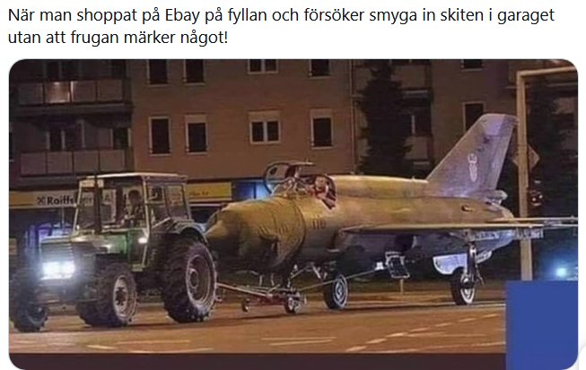 Traktor som bogserar ett gammalt stridsflygplan på en gata på natten.