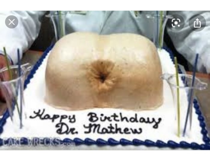 Tårta med texten "Happy Birthday Dr. Mathew" och ett stort, squashliknande föremål ovanpå.