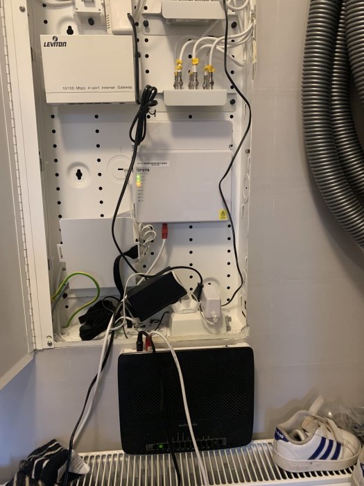 Elektriskt skåp med nätverksutrustning, kablar, router och modem i en bostad.