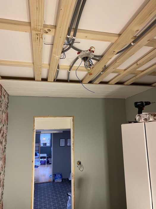 Renovering av tak med öppen träregelstomme och elinstallationer, vy mot annat rum.