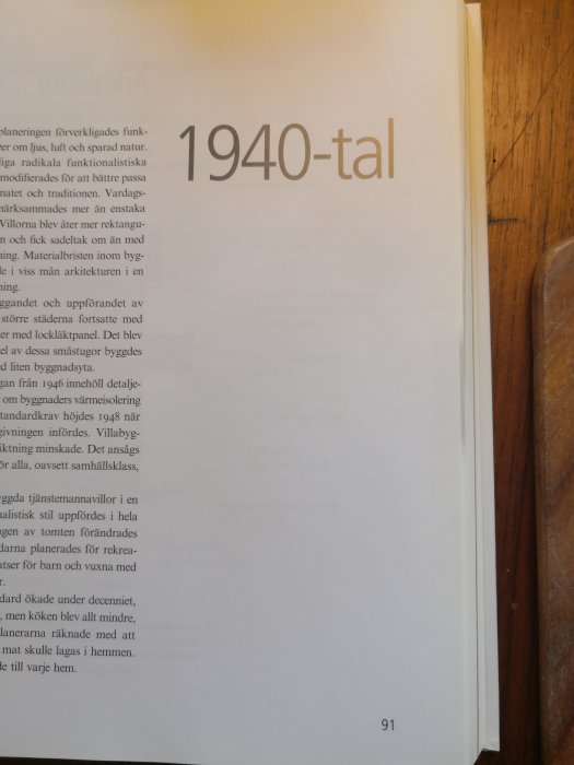 Öppen bok med text om arkitektur och byggnadsdesign från 1940-talet, bredvid den syns träkant av bokhylla.