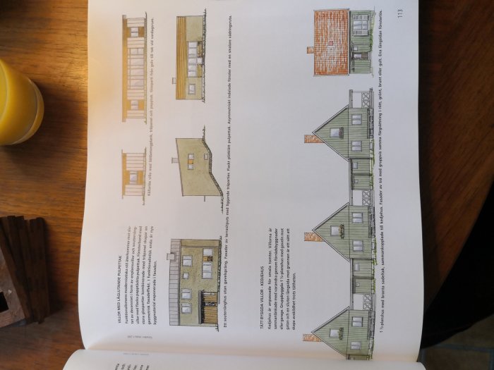 Öppen bok med arkitektritningar av ett hus visar fasader och sektioner, boken ligger på ett bord med ett glas juice.