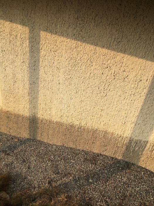 Husets kortsida med ojämn färggräns och grus intill, efterfrågar renoveringsråd.