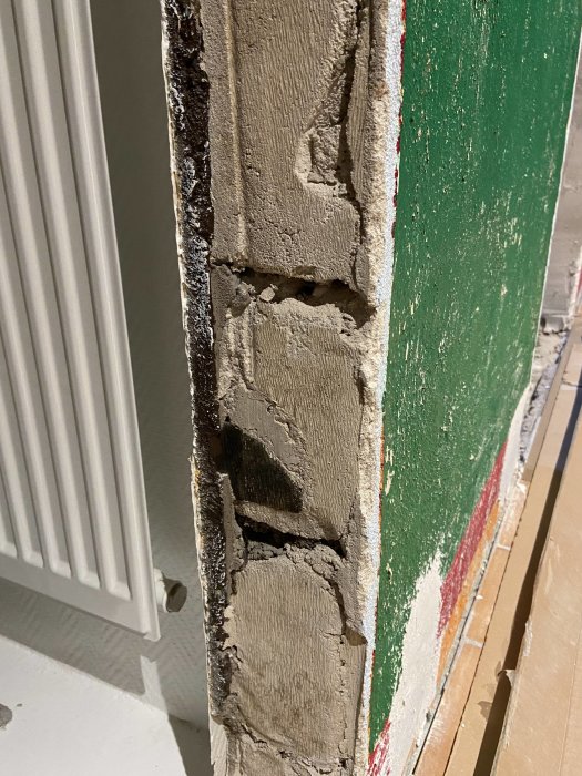 Vägg med spackel där en dörrkarm tidigare varit monterad, bredvid en radiator.