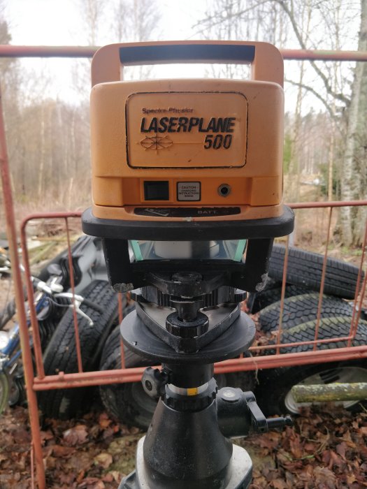 Rotationslaser Spectra Laserplane 500 monterad på ett stativ utomhus med en suddig bakgrund.